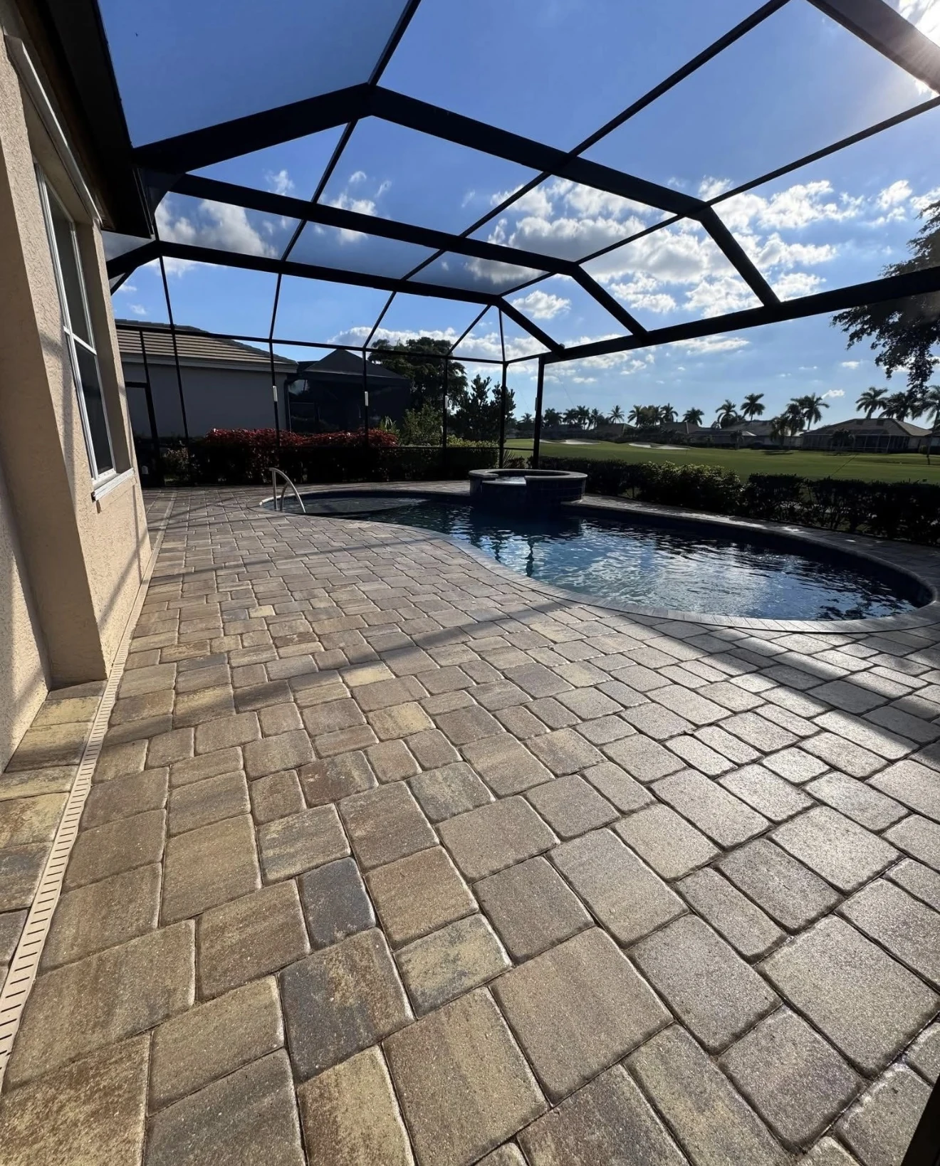 Paver pool deck beside a screened pool with a view of a lake